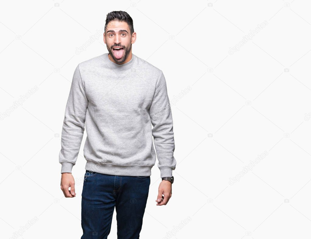 Young handsome man wearing sweatshirt over isolated background sticking tongue out happy with funny expression. Emotion concept.