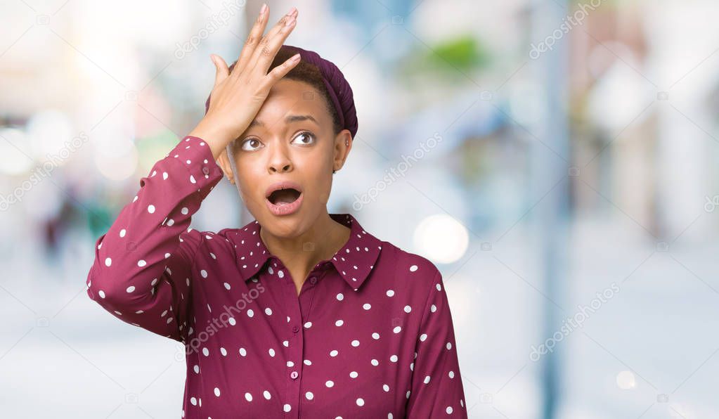 Beautiful young african american woman wearing head scarf over isolated background surprised with hand on head for mistake, remember error. Forgot, bad memory concept.
