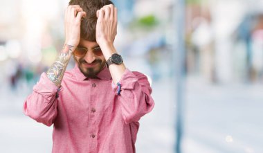 Yakışıklı delikanlı çünkü umutsuz ve stresli baş ağrısı acı izole arka plan üzerinde güneş gözlüğü takıyor ağrı ve migren. Ellerini kafasına.