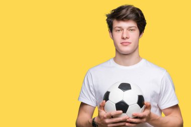 Genç adam akıllı yüzünde ciddi düşünme emin bir ifade ile izole arka plan üzerinde futbol futbol topu tutan