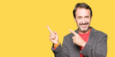 Gülümseyen ve iki elleri ve parmakları ile tarafına işaret kamera bakarak orta yaş yakışıklı iş adamı.