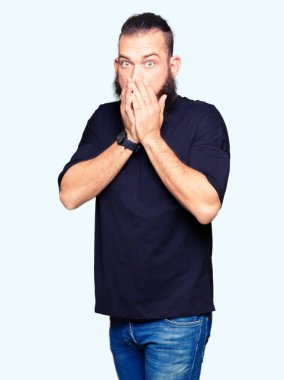 Rahat t-shirt ağız hata için elleriyle kapsayan şok giyen genç sarışın adam. Gizli kavramı.