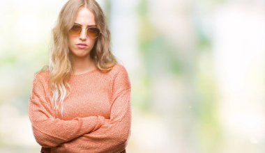 İzole arka plan şüpheci ve sinir, onaylamayan ifade yüz çapraz kolları üzerinde güneş gözlüğü takıyor güzel sarışın genç kadın. Negatif kişi.