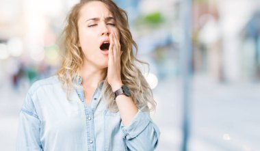 Güzel genç sarışın kadın izole arka plan üzerinde el ile ağız kapsayan yorgun esneme sıkılmış. Restless ve uyku hali.