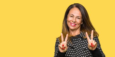 Zafer işareti yapıyor parmak gösterilen kamera seyir gülümseyen güzel orta yaş kadın giyiyor moda ceket. İki numaralı.