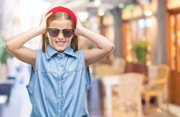 Young beautiful girl wearing sunglasses over isolated background suffering from headache desperate and stressed because pain and migraine. Hands on head.