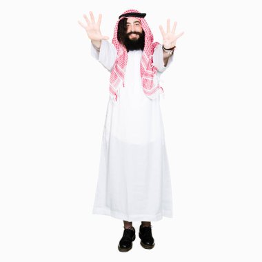 Arap iş adamı uzun saçlı gösterilen ve parmakları ile işaret geleneksel keffiyeh eşarp numara 9 kendinden emin ve mutlu gülümseyerek süre.