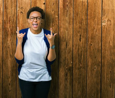 Deli ifade rock simge elle yapıyor ile bağırarak izole arka plan üzerinde gözlük takan genç güzel Afrikalı-Amerikalı kadın. Müzik yıldızı. Ağır kavramı.