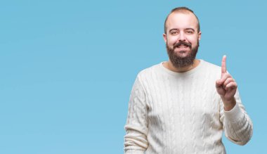 Ve kendinden emin ve mutlu gülümseyerek süre parmak numaralı yukarıyı gösteren izole arka plan üzerinde kış kazak giyen genç beyaz hipster adam.