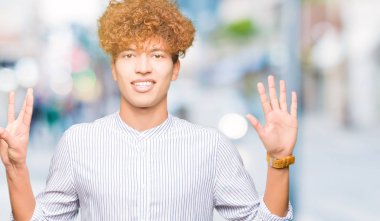 Şık gömlek gösterme ve parmakları ile işaret giyen afro saçlı Genç yakışıklı iş adamı kendinden emin ve mutlu gülümseyerek süre sekiz numara.