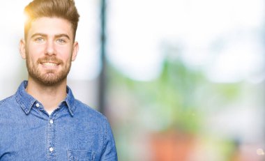 Genç yakışıklı sarışın adam neşeli sunulması ve kameraya bakarak avucunun ile işaret gülümseyen rahat kot gömlek giymiş.