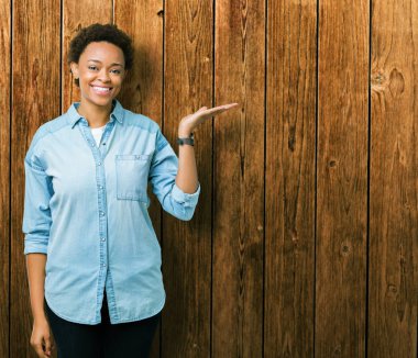 Neşeli sunulması ve kameraya bakarak avucunun ile işaret gülümseyen izole arka plan üzerinde genç güzel bir Afrikalı-Amerikalı kadın.