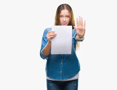Boş kağıt sayfası ile izole arka plan üzerinde tutan genç beyaz kadın dur işareti ile ciddi ve kendine güvenen ifade, savunma hareketi yaparken el açmak