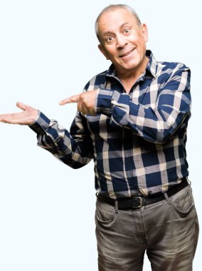 Hayret ve el ile sunulması ve parmak ile işaret ederken kameraya gülümseyen rahat gömlek giymiş yakışıklı komuta sizde.