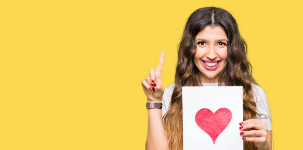 Young Adult Woman Holding Card Red Heart Surprised Idea Question — Stock Photo, Image