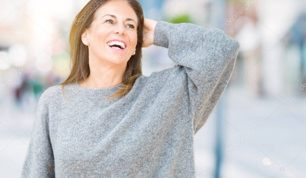 Beautiful middle age woman wearing winter sweater over isolated background Smiling confident touching hair with hand up gesture, posing attractive