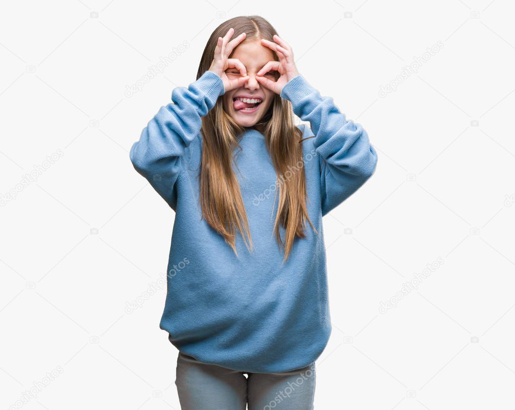 Young beautiful girl wearing winter sweater over isolated background doing ok gesture like binoculars sticking tongue out, eyes looking through fingers. Crazy expression.