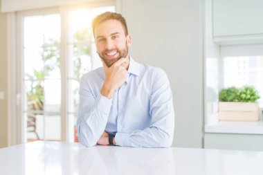 Yakışıklı iş adamı emin çapraz kollar ve çeneme kaldırdı el ile gülümseme ile kameraya bakıyor. Pozitif düşünce.