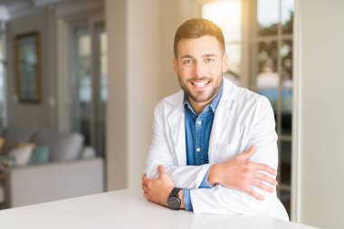 Genç yakışıklı adam kameraya bakarak çapraz silah ile gülümseyen klinik mutlu yüz, Doktor. Olumlu bir kişi.