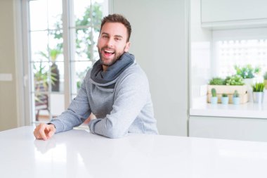 Evde rahat sweatshirt giyen ve olumlu gülümseyen yakışıklı adam