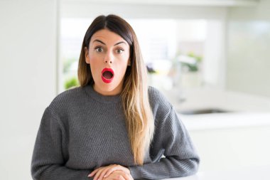 Evde korkuyor ve şok sürpriz ifade, korku ve heyecan yüz ile kış kazak giyen genç güzel kadın.