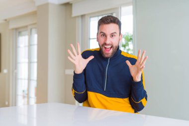 Yakışıklı adam evde deli ve başarı için hayran kaldırdı Kollarını açarak kutluyor ve heyecanlı çığlık gözleri açık. Kazanan kavramı