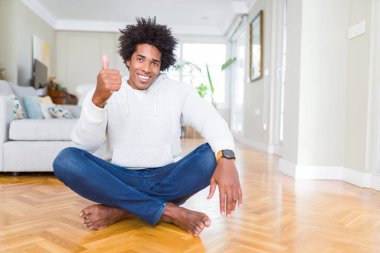 Afrika kökenli Amerikalı adam evde katta oturan hareketi el ile mutlu Yaşasın yapıyor. Kameraya bakarak başarı gösteren ile ifade onaylama.