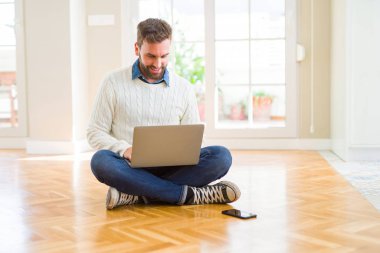 Yakışıklı adam giyen çalışma ayakta ve diş gösterilen kendine güvenen bir gülümsemeyle gülümseyerek mutlu bir yüz ile bilgisayar dizüstü kullanarak