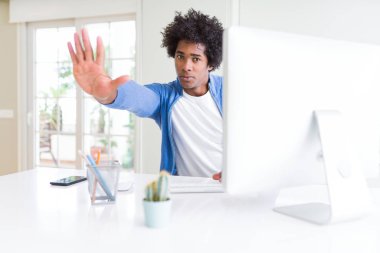 Çalışan Afrikalı-Amerikalı erkeğin açık eliyle dur işareti ile ifade, ciddi ve kendinden emin yaparken bilgisayar kullanarak savunma jest