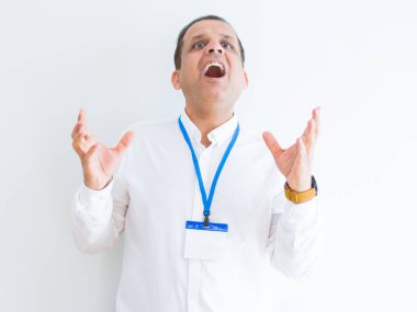 Orta yaş iş adamı beyaz arka plan çılgın ve kızgın bağırarak ve agresif ifade ve silah kaldırdı bağırmaya üzerinde kimlik kartı takıyor. Hayal kırıklığı kavramı.