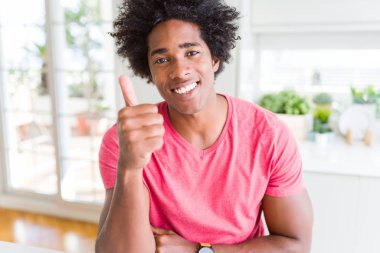 Hareketi el ile mutlu Yaşasın yapıyor pembe rahat t-shirt giyen ABD'li iş adamı. Başarı gösteren kameraya bakarak ifade onaylama.