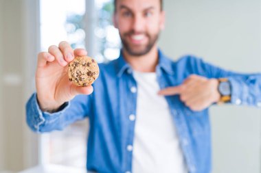 Yakışıklı adam yeme çikolata Çerezler sürpriz yüz işaret parmağı kendisine fişleri