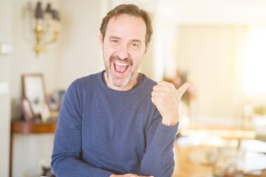 Seyir ve başparmak yanında yukarıyı mutlu yüz ile yakışıklı orta yaş erkek ev gülümseyen.