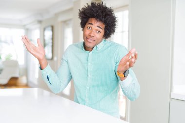 Afrika kökenli Amerikalı iş adamı şık gömlek clueless ve şaşkın bir ifadeyle kollar ve eller kaldırdı giyiyor. Şüphe kavramı.