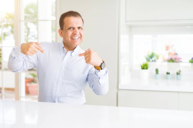 Evde oturan orta yaş kendini gururlu ve mutlu parmakları ile işaret emin yüz, gülümseme ile seyir.