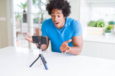Bir sürpriz yüz, korkuyor ve heyecanlı korku ifadesi ile smartphone şokta korktuğunu kullanarak web kamerası ile online arama yapan Afro-Amerikan erkek