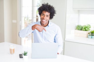 Afrika kökenli Amerikalı iş adamı sürpriz ile dizüstü bilgisayar kullanarak çalışma yüz kendine işaret parmağı