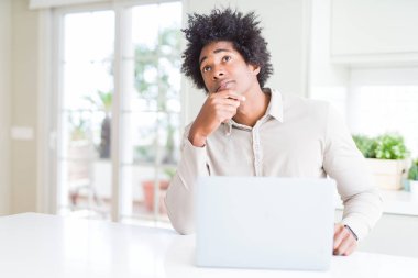 Dizüstü ciddi bir yüz düşünme soru hakkında çok kullanarak çalışan Afrikalı-Amerikalı erkeğin fikir karışık