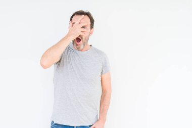 Mahcup ifadeyle parmaklarımın arasından seyir yakışıklı komuta sizde yüz ve gözler el ile kapsayan şok bakmak izole arka plan üzerinde.