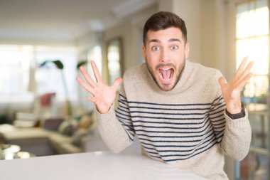 Genç yakışıklı adam evde deli ve başarı için hayran kaldırdı Kollarını açarak kutluyor ve heyecanlı çığlık gözleri açık. Kazanan kavramı