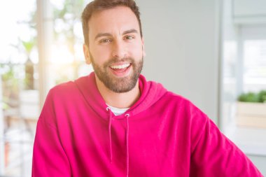 Evde rahat sweatshirt giyen ve olumlu gülümseyen yakışıklı adam