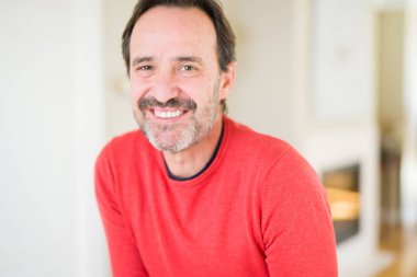 Evde kameraya bakarak gülümseyen yakışıklı orta yaş erkek