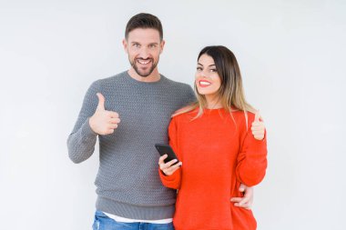 Genç çift ok işareti yapıyor büyük gülümseme ile izole arka plan üzerinde mutlu Smartphone kullanarak parmak ile mükemmel işaret parmak