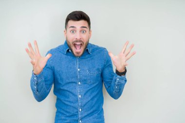 Yakışıklı delikanlı deli kutluyor ve silah ile başarı için heyecanlı çığlık kaldırdı ve açık gözleri hayret izole arka plan üzerinde. Kazanan kavramı