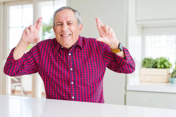 Hombre Mayor Guapo Casa Sonriendo Cruzando Los Dedos Con Esperanza — Foto de Stock