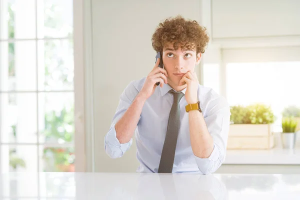 Joven Hombre Negocios Hablando Teléfono Inteligente Oficina Cara Seria Pensando — Foto de Stock
