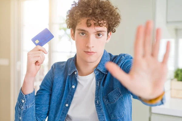 防衛ジェスチャー 深刻な自信を持って式に一時停止の標識を行うオープン手でクレジット カードを保持している若い男 — ストック写真