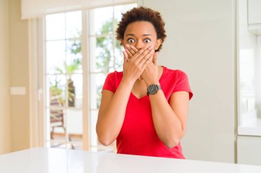 Young beautiful african american woman at home shocked covering mouth with hands for mistake. Secret concept. clipart