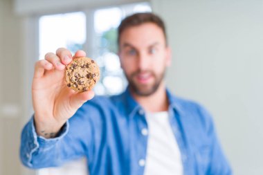 Yakışıklı adam çikolata Çerezler bir sürpriz yüz, korkuyor ve heyecanlı korku ifadesi ile şok korkmuş yeme