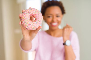 Duygu tezahürat genç Afro-Amerikan kadın gurur çığlık ve zafer ve başarı çok heyecanlıyız, kutlayan pembe şeker donut yemek
